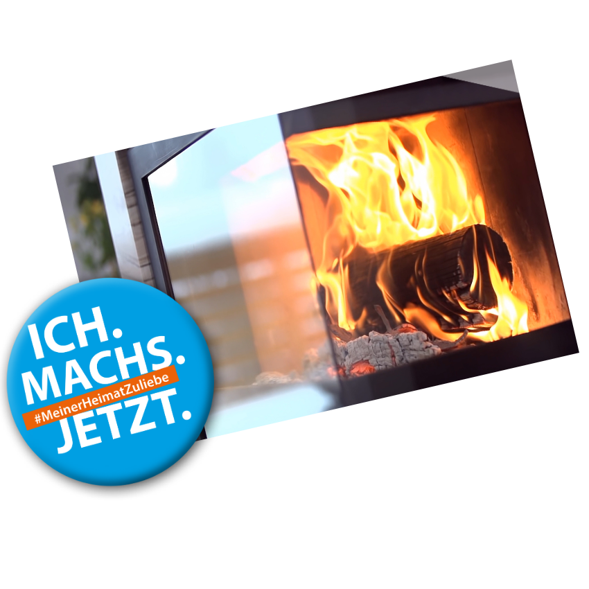 Badge mit Text: "Ich machs jetzt #MeinerHeimatZuliebe" auf einem Bild in dem Feuer in einem Kamin brennt
